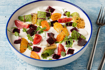 Colorful yogurt salad with grilled oranges, beets, cherry tomatoes, and greens