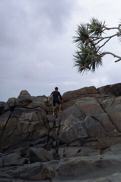 Side view of man with surfboard standing by rock