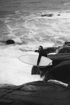 Man with surfboard standing on rock