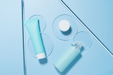 Natural cosmetic laboratory concept. Petri dish with cosmetic cream, blue cream tube and face oil bottle on blue background top view, mockup