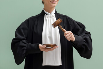 Judge with mallet and sound block on light green background, closeup