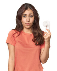 Middle Eastern woman with facial cleanser shrugs shoulders and open eyes confused.
