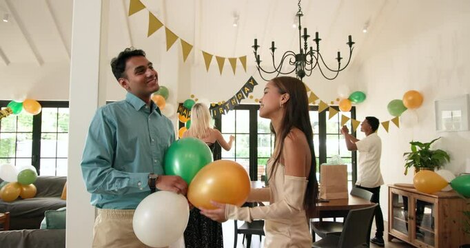 Group of happy multiracial, white and indian male and female friends preparing decorations for a bir