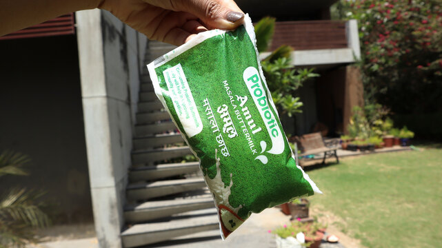 Hands holding Amul probiotic buttermilk, a refreshing milk based natural drink packed in pouch