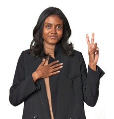 Young Indian woman in business suit taking an oath, putting hand on chest.
