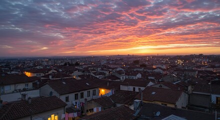 Dramatic sunrise paints the sky over a European city with tiled rooftops