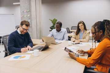 Professional team discussing strategy, reviewing analytics on digital devices during collaborative meeting in modern workplace setting