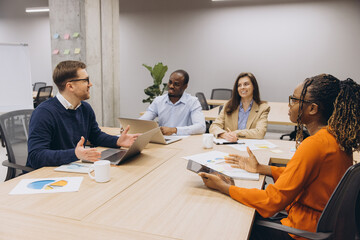 Business professionals analyzing financial data, collaborating in contemporary workspace, sharing insights and strategic planning