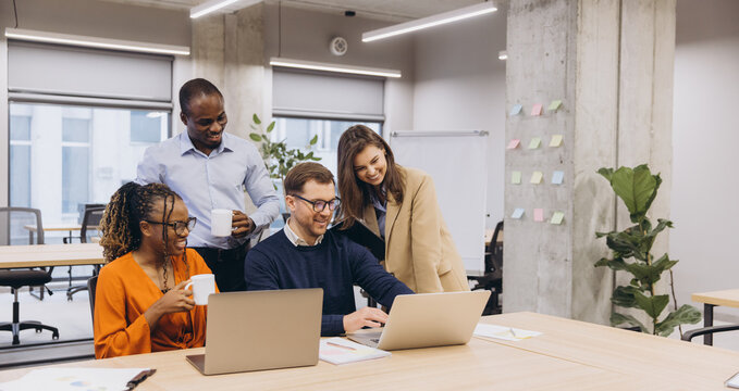 Professional team collaborating, sharing innovative ideas with laptops in contemporary workplace, representing diverse workforce dynamics - Powered by Adobe