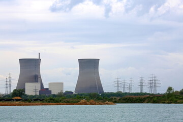 Das Atomkraftwerk Gundremmingen. Die imposanten Kühltürme stehen im Hintergrund und dominieren die Szene mit ihrer markanten hyperbolischen Form. Im Vordergrund erstreckt sich ein Gewässer