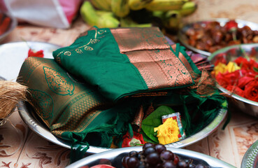Traditional South Indian silk saree with betel leaves, flowers, and fruits arranged in a ceremonial plate during a cultural event like puberty function, wedding, or religious ritual.