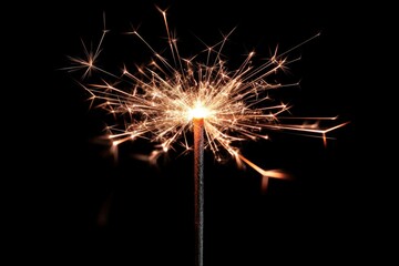 Close-up of a festive sparkler burning against a black background, creating a dazzling display of light and sparks, studio shot