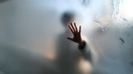 Foggy glass with male figure pressing palm against surface