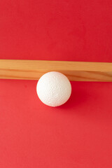 Still life with wooden block and a a plastic foam ball on red background	