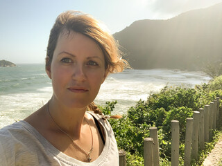 Woman Taking Coastal Selfie with Windy Hair and Scenic Ocean View