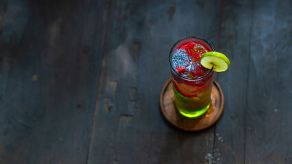 Refreshing iced nutmeg juice or pala juice with colorful jelly and syrup in highball glass, on wood surface, with shallow depth of field