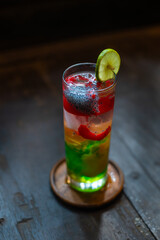 Refreshing iced nutmeg juice or pala juice with colorful jelly and syrup in highball glass, on wood surface, with shallow depth of field