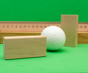 Still life with wooden blocks and a a plastic foam ball on green background	