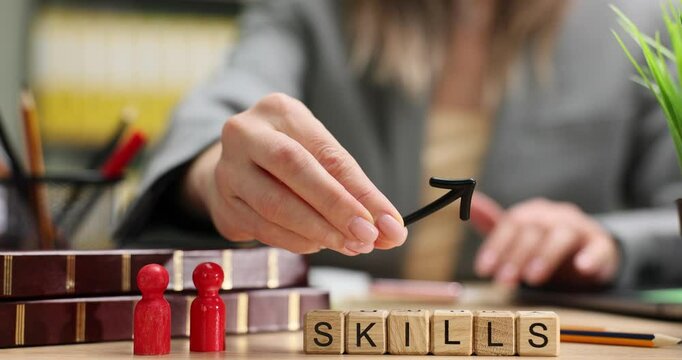 Woman moves upward arrow by wooden blocks with word Skills on desk in office. Concepts of professional development and career growth slow motion