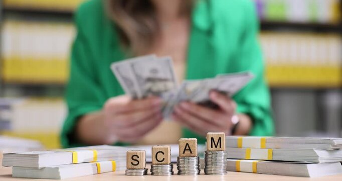Businesswoman counts money at word Scam from wooden cubes and placed on coins steps. Concept of financial fraud and illegal money making schemes