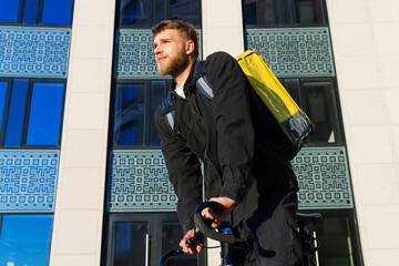 A male courier in the city. Fast delivery from restaurants by bike. Ecological transport