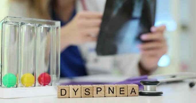 Term Dyspnea from wooden blocks and incentive spirometer on doctor desk. Physician holds X-ray image checking respiratory health in clinic
