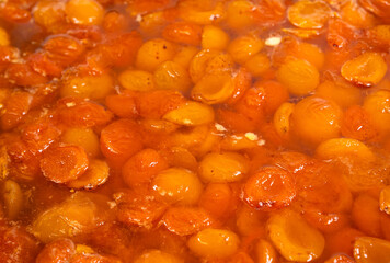 Apricot jam simmering in a large pot at a sunny kitchen in the countryside during summer