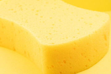 Bright yellow sponge resting on a matching background showcasing its texture and contours