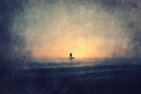 Solitary figure on a surfboard at sunset, peaceful ocean scene.