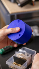 Hands of a South Asian man examining a cobalt plastic creation evokes Diwali-inspired innovation; quirky artifact for World Maker Faire, 3D printer, 3D printing