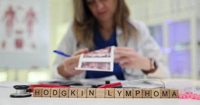 Phrase Hodgkin Lymphoma on wooden blocks against doctor analyzing medical scans. Physician woman diagnoses dangerous disease in hospital office