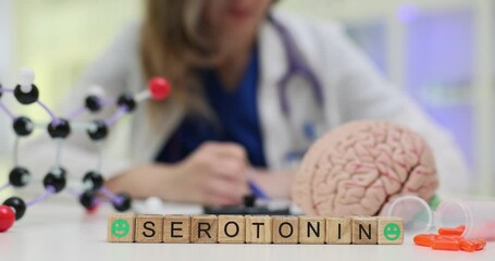 Word Serotonin on wooden blocks with smileys by molecular model against working doctor. Medical specialist documents prescription at clinic workplace - Powered by Adobe