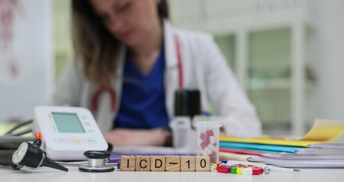 Text ICD-10 on wooden cubes by medical equipment and tonometer against woman doctor. Medic uses diagnostic coding system for healthcare documentation