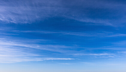 An expansive view of a clear blue sky, featuring thin, wispy cloud