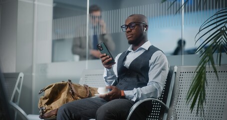 Airport Terminal: Successful Entrepreneur Using Smartphone and Drinking Coffee. African American...