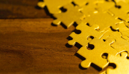 Golden puzzle pieces spill onto a rich wood surface, symbolizing solutions, unity, and connection. Ideal for business, strategy, or teamwork concepts.