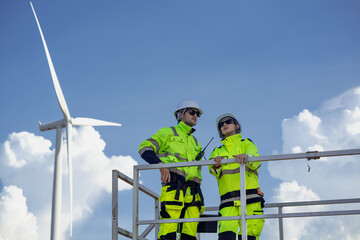 Maintenance engineer team standing at windmills at wind turbine farm. Group of people wear safety...