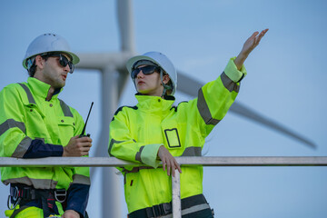 Maintenance engineer team standing at windmills at wind turbine farm. Group of people wear safety...