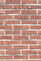 vertical shot of weathered red brick surface with textured wall pattern with mortar lines, ideal element for layout, design and smartphone wallpaper, sunny day