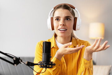 Young woman recording podcast wearing headphones and speaking into microphone