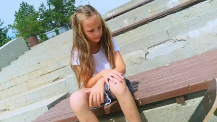 In a good sunny day in the middle of the skate park little girl rests before start a ride. 4k