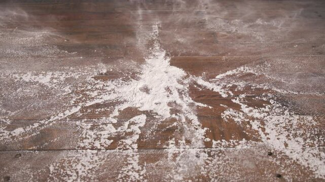 Hands going back and forth smacking a pile of flour on a table in slow motion.