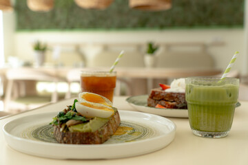 Avocado toast with soft boiled egg, matcha latte and french toast served on a table in a modern restaurant, enjoying a healthy breakfast or brunch