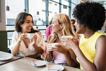 Happy girls drinking a coffee and laughing while chatting relaxed
