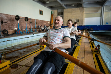 Dedicated powerful athletic rowers in perfect synchronization stroking puddling on indoor rowing...