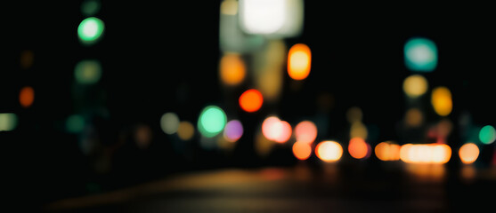 Blurred city lights at night create a bokeh effect on a dark background.