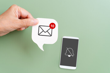 hand hold incoming mail sign on real white speech bubble paper cut with no sound reminder sign on white mobile phone with green background