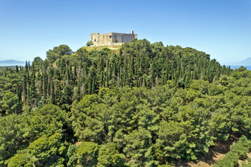 Aerial view of medieval Chlemoutsi Castle and coastal village landscape in Peloponnese, Greece, Europe, with sea and forested hills in the background.