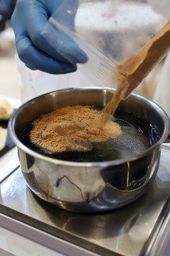 chef echando un sobre de ingredientes preparados en una cacerola de la cocina para elaborar un guiso de sopa