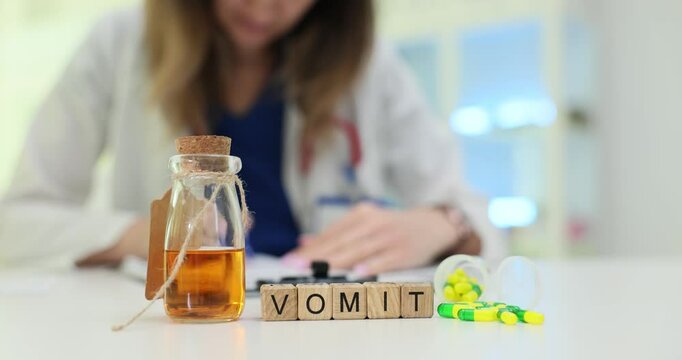 Woman writes recommendations for patient against wooden cubes with Vomit and medicines on table. Preparation of medication to treat vomiting